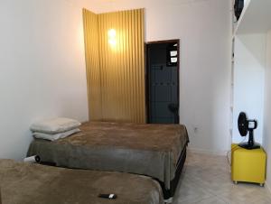 a room with two beds and a door to a bathroom at Sítio Moriá in Camaçari