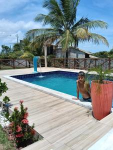 a man sitting in a pool next to a palm tree at Sítio Moriá in Camaçari +3 photos