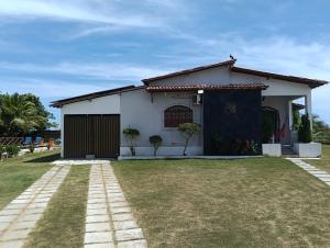 a small white house with a grass yard at Sítio Moriá in Camaçari