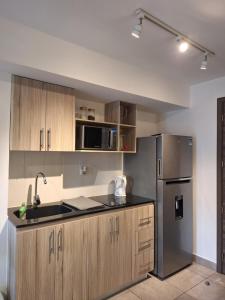 a kitchen with wooden cabinets and a stainless steel refrigerator at Flamingo zona 4 in Guatemala