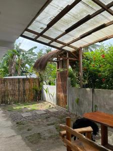 a wooden pergola with a wooden table and a bench at Chia's Beach House Siargao in Cabalawan