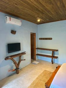 a room with a bed and a desk with a television at Odoyá Corumbau in Corumbau