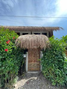 a small hut with a straw roof and a door at Chia's Beach House Siargao in Cabalawan