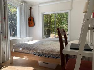 a bedroom with a bed and a desk and a guitar at Retreat in a beautiful forest! in McMahons Creek