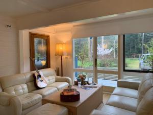 a living room with two couches and a guitar at Retreat in a beautiful forest! in McMahons Creek