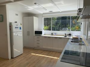 a kitchen with a white refrigerator and a window at Retreat in a beautiful forest! in McMahons Creek