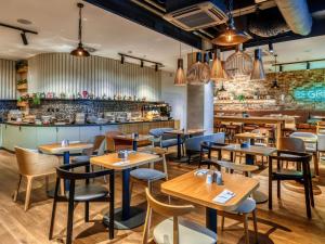 a restaurant with wooden tables and chairs and a bar at Mercure Katowice Centrum in Katowice