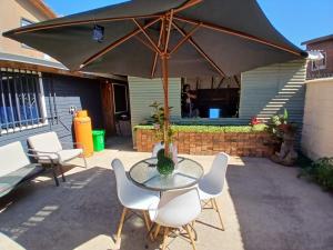 a table with chairs and an umbrella on a patio at Los Camperos AR in Temuco