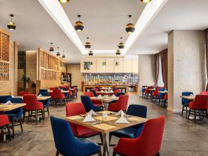 un ristorante con tavoli e sedie rossi e blu di Novotel Makkah Thakher City a La Mecca