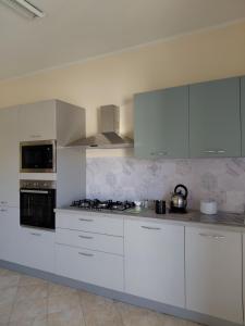 a kitchen with white cabinets and a stove top oven at La Terrazza Apartment in Cosenza