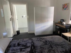 a bedroom with a bed and white cabinets and a desk at Commercial Hotel Parkes in Parkes