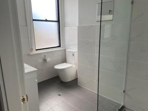 a white bathroom with a toilet and a window at Commercial Hotel Parkes in Parkes