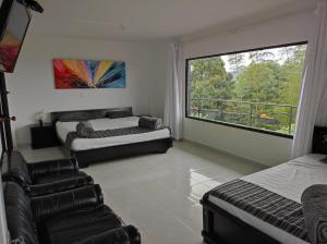 two beds and a couch in a room with a window at Finca Villa Lake in Horizonte