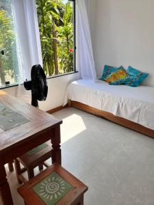 a room with a bed and a table and a window at Casa Liz in Itacaré