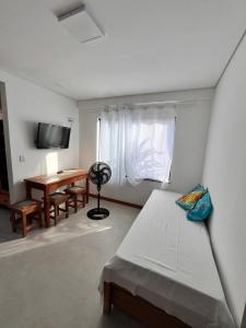 a room with a bed and a table and a desk at Casa Liz in Itacaré