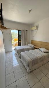 two beds in a hotel room with a balcony at Residencial Vista Bela in Bombinhas +214 photos