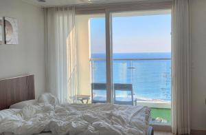 a bedroom with a bed and a view of the ocean at 속초 오션뷰 써밋베이1205 in Sajin