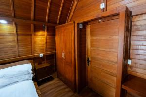 a small room with a bed and wooden walls at Villa Kartikasari in Munduk