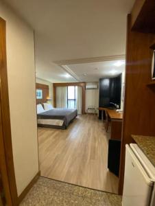 a bedroom with a bed and a desk and a television at Lindo flat Grand Mercoure triplo in Brasília