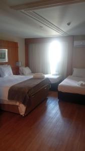 a hotel room with two beds and a window at Lindo flat Grand Mercoure triplo in Brasília