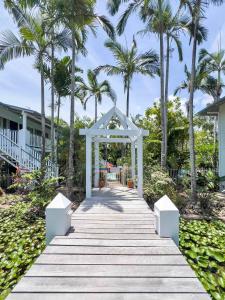 a wooden boardwalk leading to a beach with palm trees at Poolside Mango House in Airlie Beach