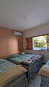 three beds in a room with a window at Recanto Ebenézer in Taipu
