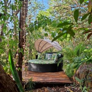 a bench with an umbrella on a wooden deck at Cocolhu Treehouse & Ocean View in Tamarindo