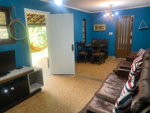 a living room with a couch and a television at Casa com 2 Piscinas infantil e adulto a 450m da Praia Até 15 Pessoas in São Sebastião