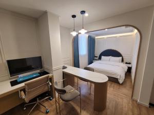a bedroom with a bed and a desk with a television at Hotel Label Seongnam in Seongnam