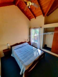 a bedroom with a bed with a ceiling fan and a window at Balcón del Cerro Cabañas in La Falda
