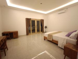 a bedroom with a large bed and a table and a table sidx sidx at Dharma Yoga Guest House Amed in Amed