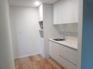 a kitchen with white cabinets and a sink at Dream House 5 in Auckland