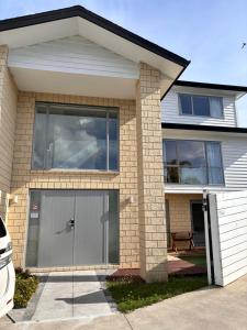 a house with a gray garage door in front of it at Dream House 5 in Auckland