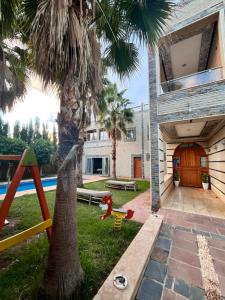 a house with a palm tree and a playground at Villa Gomez in Sbiti +2 photos