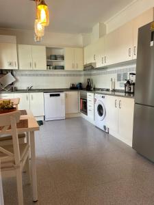 a kitchen with white cabinets and a washer and dryer at House near Ribeira with Garden, Terrace & Yoga Studio in Santo Isidoro