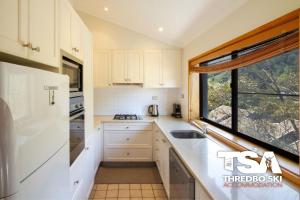 a kitchen with white cabinets and a window at Mowamba E6 in Thredbo