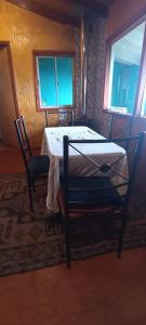 a room with a table and a chair and two windows at Cabaña Quiroz in Valdivia