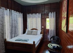 a bedroom with a bed with wooden walls and a window at Panpim Resort in Ban Noen Hom