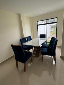 a dining room with a white table and blue chairs at Confortable casa independiente in Crucita