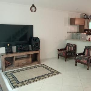 a living room with a flat screen tv and two chairs at Enseada Perto da praia Guarujá com vaga de garagem in Guarujá