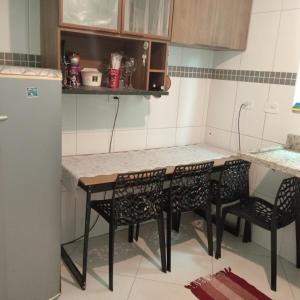 a kitchen with a table and chairs and a refrigerator at Enseada Perto da praia Guarujá com vaga de garagem in Guarujá +17 photos