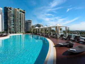 una piscina con sedie e ombrelloni su un edificio di Sofitel Gold Coast Broadbeach a Gold Coast