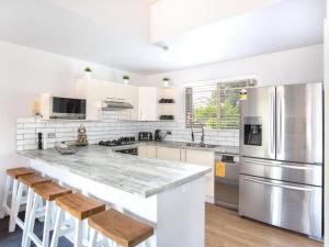 a kitchen with stainless steel appliances and wooden stools at Fairway Haven Getaway in Mollymook +27 photos
