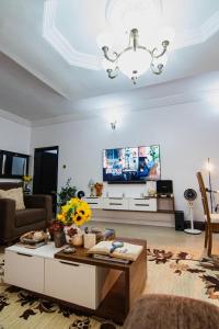 a living room with a chandelier and a tv at Suitehub in Ikeja