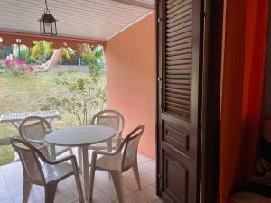 a table and chairs on a patio with a table and a window at Camellia 2 Duplex in Sainte-Anne