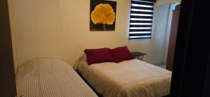 a bedroom with two beds with red pillows and a window at Departamento Ruze Privado-Tranquilo in Plan Libertador