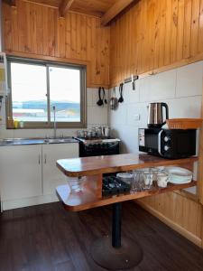 een keuken met een tafel, een magnetron en een fornuis bij Cabañas Mc Chelo Pelluhue in Pelluhue