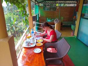 a woman sitting at a table eating food at Rainforest View in Deniyaya