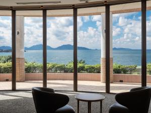 een kamer met ramen met uitzicht op de oceaan bij KAMENOI HOTEL Genkainada in Kitakyushu