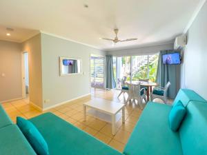 a living room with a blue couch and a table at Mango Reef House - Airlie Beach in Airlie Beach